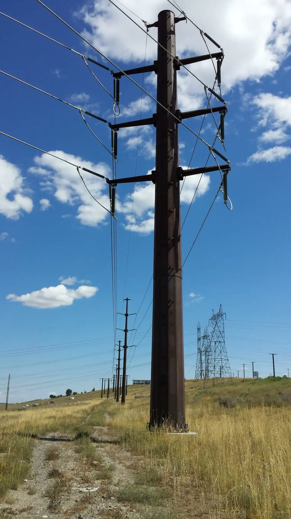 Weathering steel transmission pole with three crossarms in dry grassland