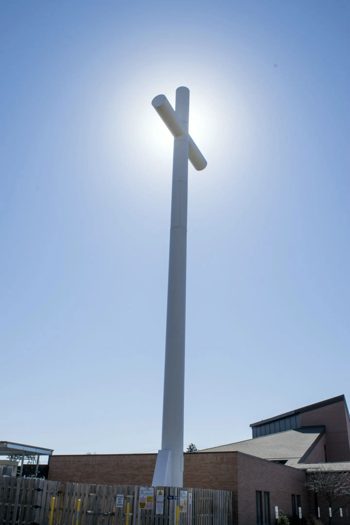 Tall white steel cross structure beside a church building