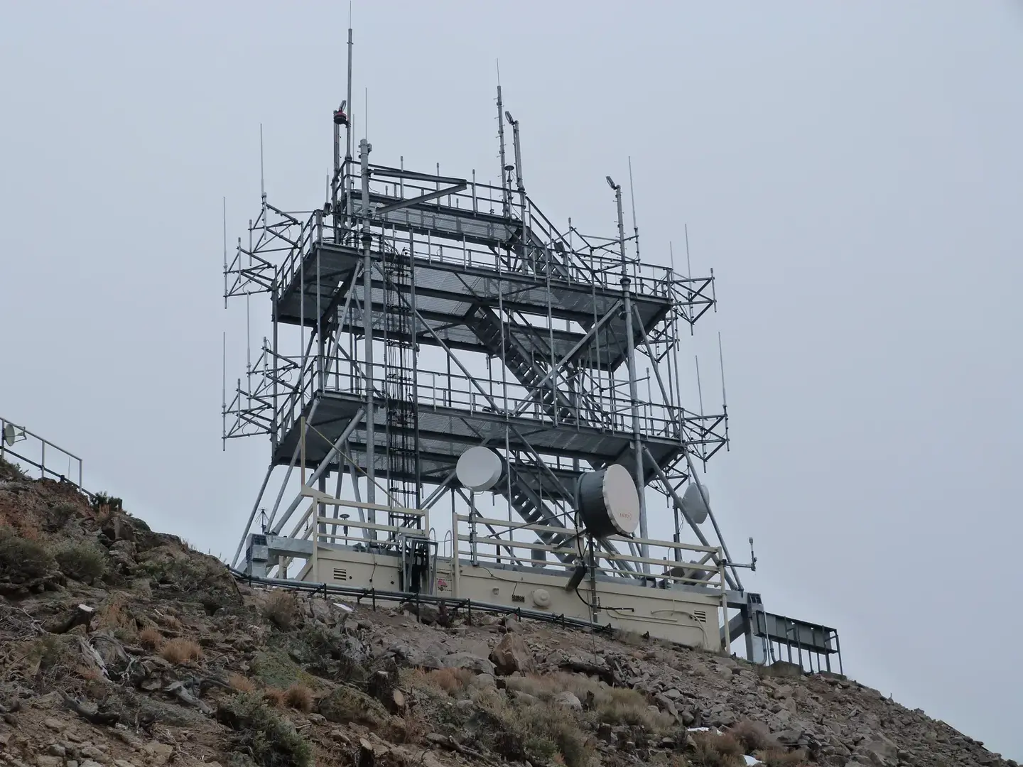 Steel communications tower platform carrying microwave dishes on a rocky hilltop