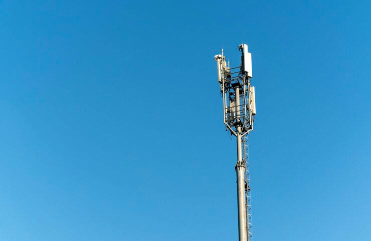 Steel monopole topped with an antenna array against a clear blue sky